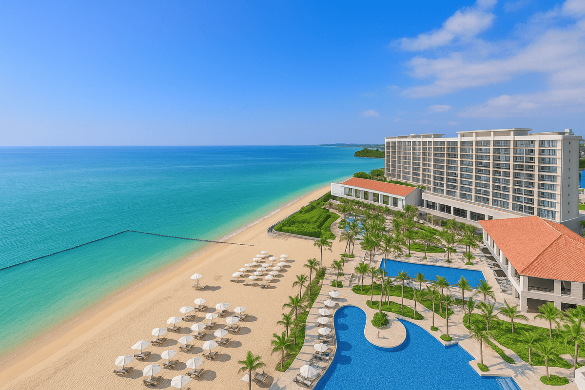 Beachfront resort in Okinawa with turquoise sea, golden sand, sun loungers, and palm trees under a bright blue sky